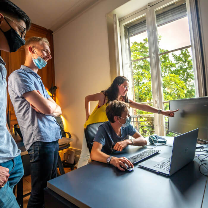 Projektmanagerin zeigt dem Team auf dem Monitor was sie wann zu tun haben.