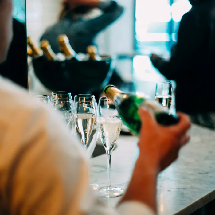 Kellnerin schenkt in einem Restaurant drei Gläser Sekt ein