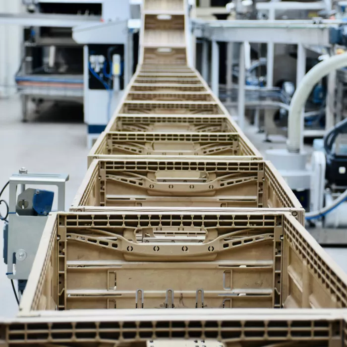 Innerhalb eines Apfelverarbeitungsunternehmens in Norditalien arbeiten viele Produktionsmitarbeiter. Hier laufen diverse Apfelkisten vom Band, bevor die Äpfel kommen.