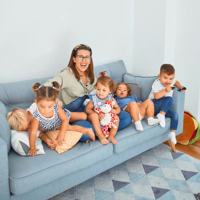 Erzieherin im Kindergarten mit Ihrer Kindergruppe. Sie freut sich und lacht dabei.