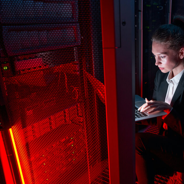 Hübsche Netzwerkadministratorin im rot beleuchteten Serverraum.