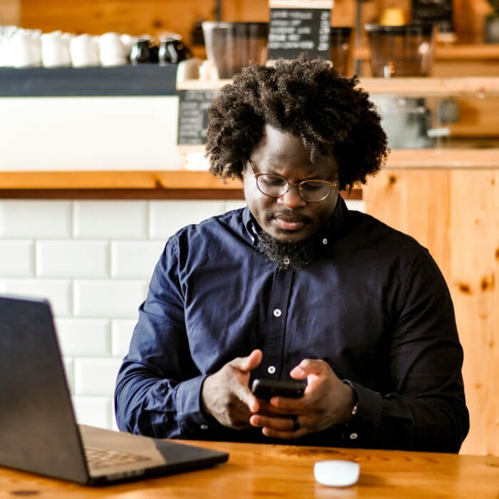 Vertriebsmitarbeiter im Außendienst tippt etwas auf seinem Handy in einem Café
